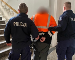 zatrzymany w kajdankach prowadzony przez dwóch umundurowanych policjantów