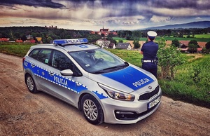radiowóz obok którego stoi policjantka z ruchu drogowego, w tle powiat ząbkowicki