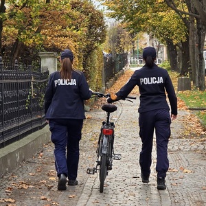 2 policjantki umundurowane prowadzą po chodniku rower