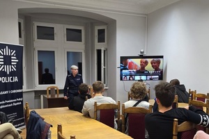 spotkanie z młodzieżą na terenie KPP Ząbkowice Śląskie. Młodzież siedzi na krzesłach tyłem w pomieszczeniu, na przeciwko nich policjantka umundurowana