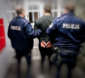 dwóch policjantów prowadzących skutego, zatrzymanego mężczyznę