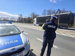 policjant mierzący prędkość przy radiowozie