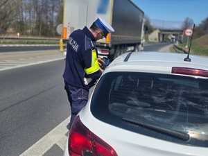 policjant z ręcznym miernikiem prędkości na drodze