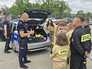 promocja zawodu policjanta na pikniku ohp w Budzowie w dniu 10.05.2025 , policjanci umundurowani z młodzieżą przy radiowozie