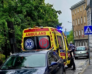 policjantka umundurowana z dzieckiem na ręku, na ulicy przy karetce pogotowia
