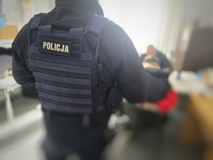 zatrzymany siedzi na krześle w asystencie policjantów