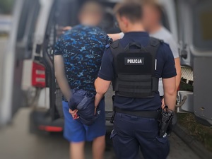 zatrzymany poszukiwany mężczyzna prowadzony przez umundurowanego policjanta