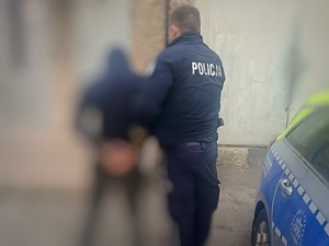 zatrzymany mężczyzna w kajdankach trzymane przez policjanta umundurowanego
