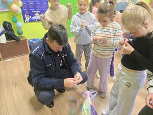 spotkanie z dziećmi w klasie,policjant pokazuje jak założyć odblaski