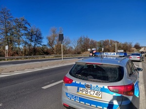 policjant umundurowany przy radiowozie z ręcznym miernikiem prędkości