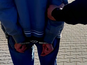 zatrzymany w kajdankach założonych na ręce trzymane z tyłu