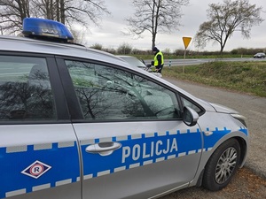policjant zatrzymał samochód osobowy do kontroli, na 1 planie radiowóz