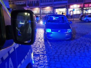 radiowóz bok na pierwszym planie, na palnie drugim samochód osobowy