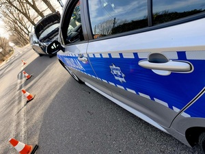 zabezpieczenie miejsca zdarzenia drogowego przez policję, na 1 planie radiowóz