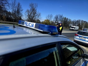 policjant umundurowany przy radiowozie mierzy prędkość