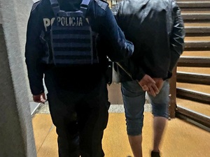 zatrzymany za narkotyki mężczyzna w kajdankach prowadzony przez policjanta w pomieszczeniu