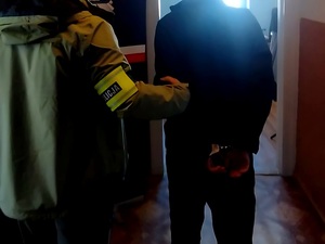 mężczyzna w kajdankach prowadzony przez nieumundurowanego policjanta