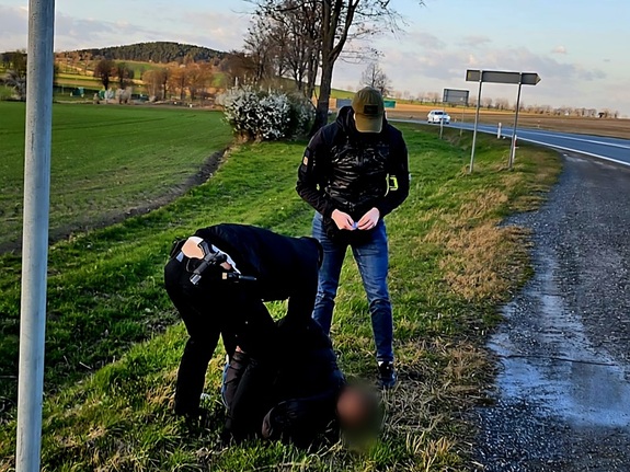 zatrzymany leży na trawie przy drodze, obok policjanci