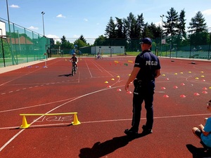 policjant przeprowadzający egzamin na kratę rowerowa w szkole z dziećmi