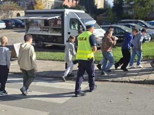 policjant przeprowadza grupkę dzieci przez pasy