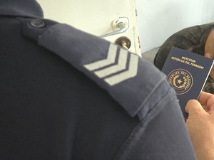 policjant trzymający paszport paragwajski w tle mężczyzna
