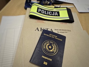 akta, opaska z napisem policja i paragwajski paszport