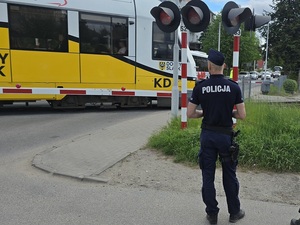 przejazd kolejowy zamknięty, rogatki opuszczone, policjant umundurowany